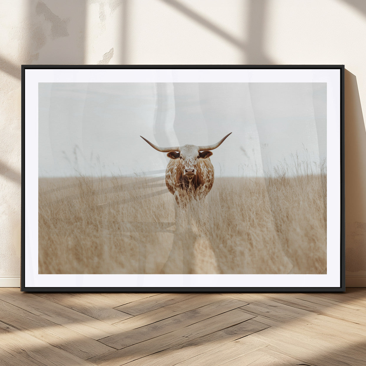 Texas Longhorn bull standing alone in dry grass with neutral tones, ideal for rustic western or cowboy-themed wall decor.