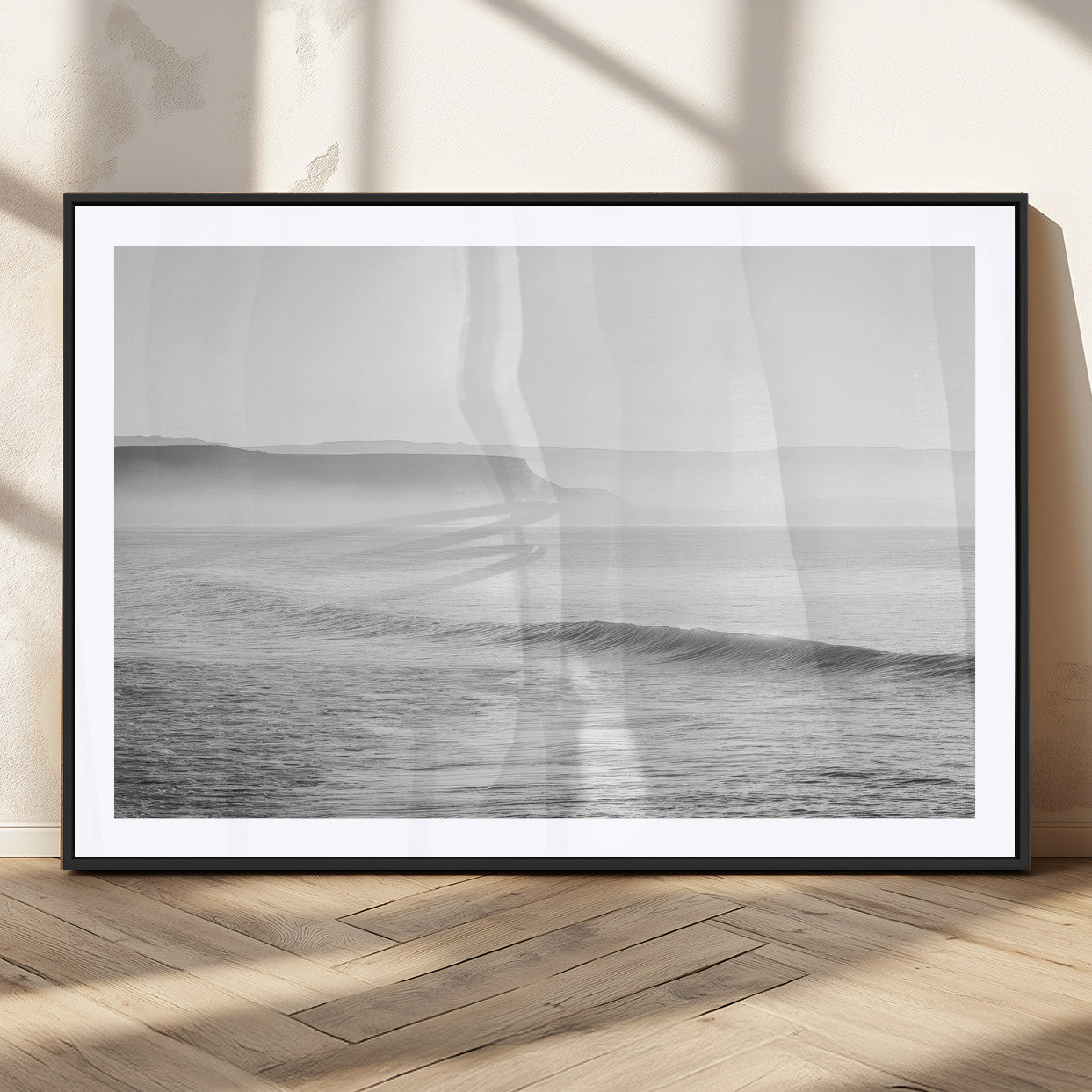 A black and white minimalist seascape featuring soft rolling waves and misty distant cliffs, creating a serene and timeless coastal atmosphere.