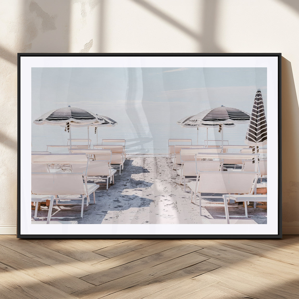 A serene minimalist beach scene featuring striped umbrellas, soft pastel sand, and an elegant lounge setup, creating a tranquil and stylish coastal retreat.
