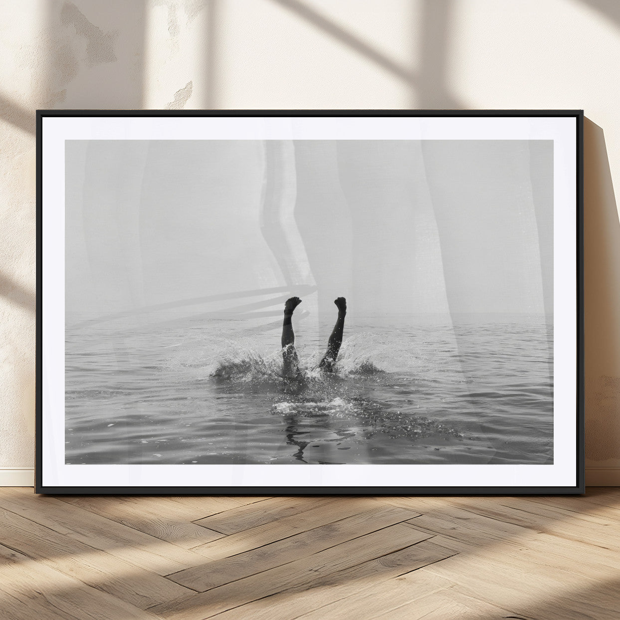A black and white minimalist water scene capturing a playful splash as a swimmer dives upside down, creating a carefree and artistic aquatic aesthetic.
