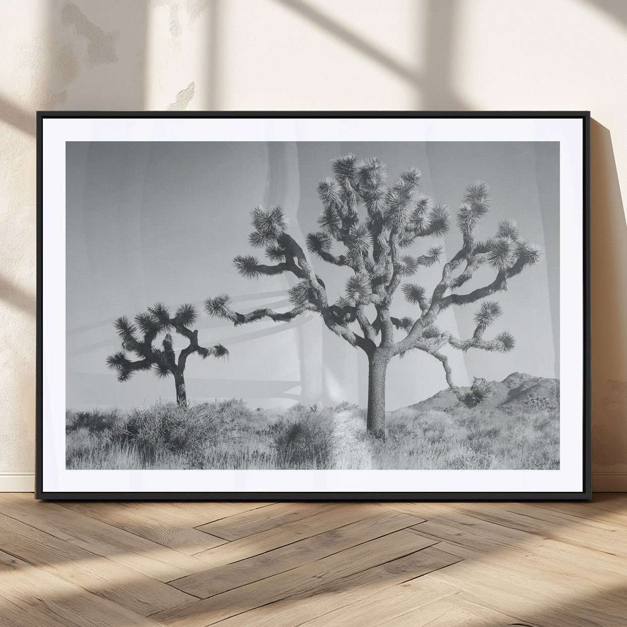Two Joshua trees in a black and white desert landscape with distant hills, ideal for boho or rustic interior wall styling.