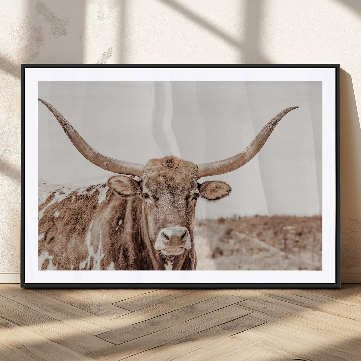 A longhorn cow in soft beige desert tones, standing calmly in open land, perfect for neutral western or rustic farmhouse interiors.