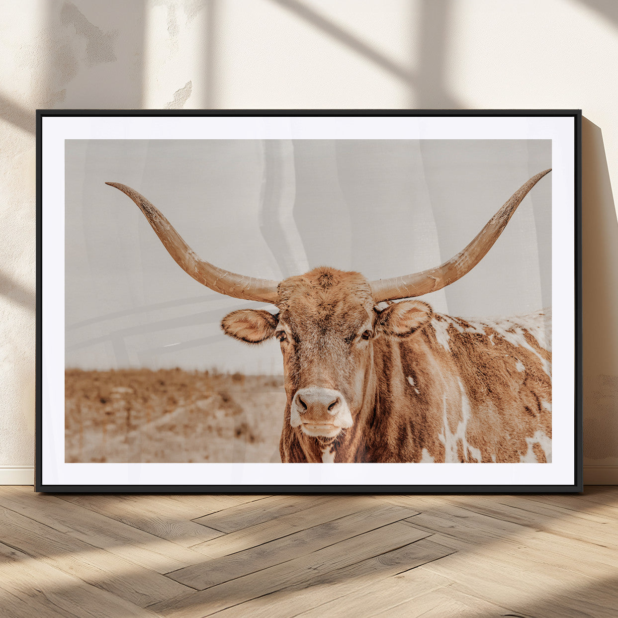 A longhorn bull standing proudly in a sunlit desert field with warm neutral tones, ideal for rustic western or farmhouse interiors.