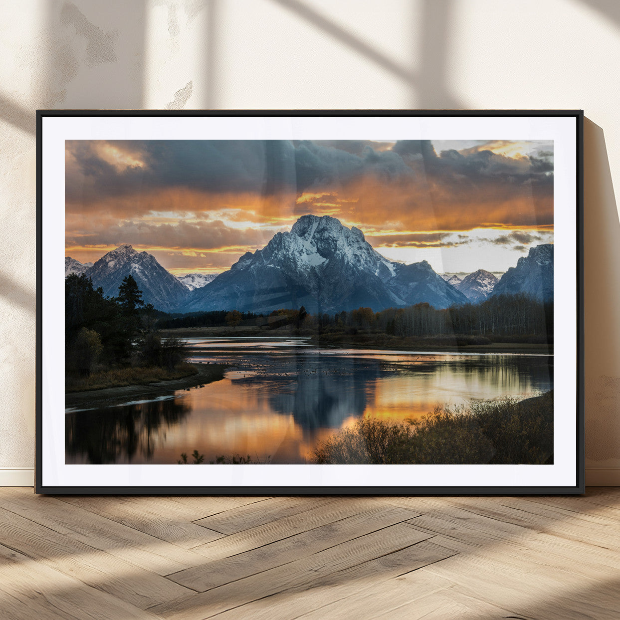 Snow-capped mountains reflecting in a calm lake at sunset, with a dramatic golden sky creating a breathtaking wilderness scene.