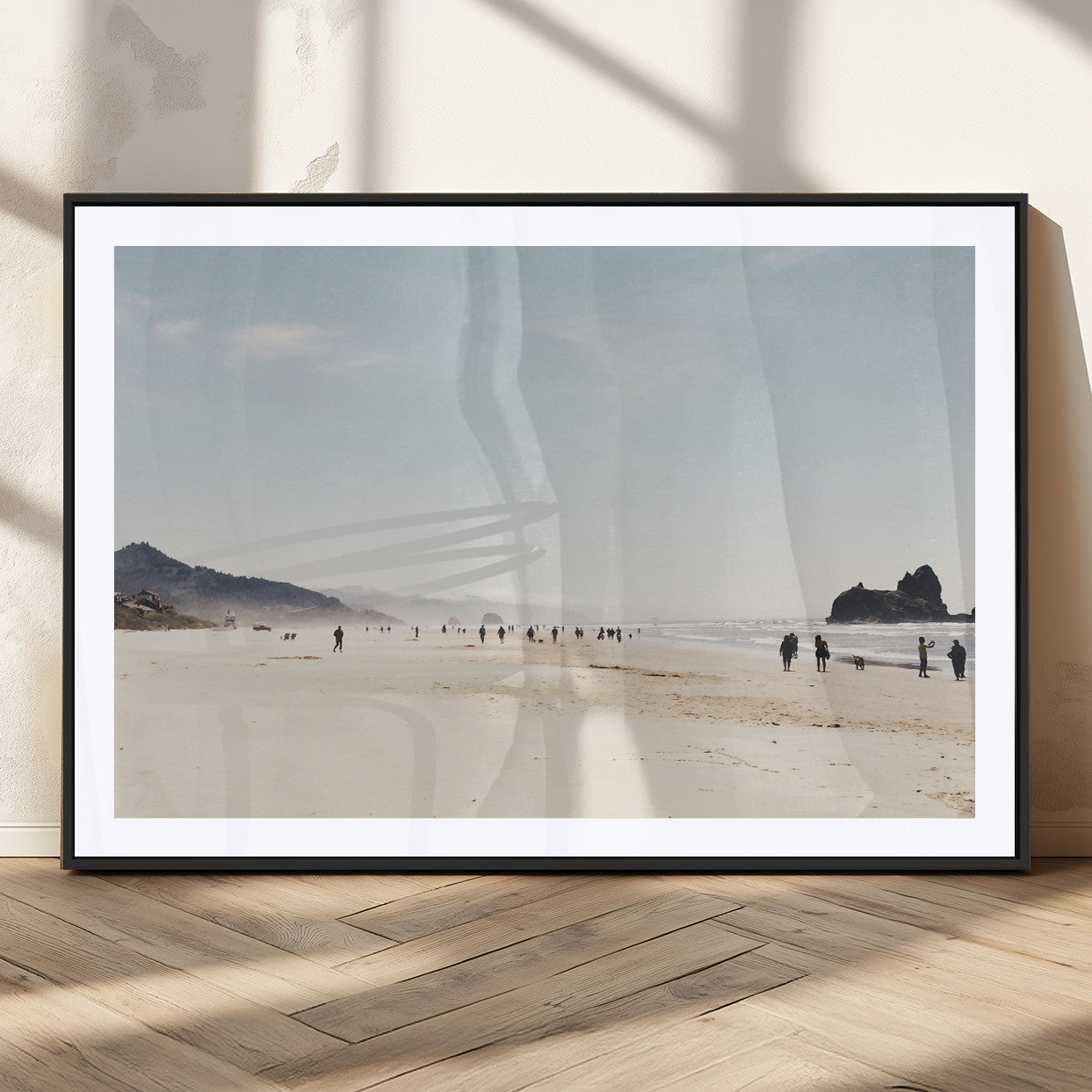 A serene beach with soft sand, misty mountains, and scattered people walking along the shoreline, creating a peaceful coastal landscape.
