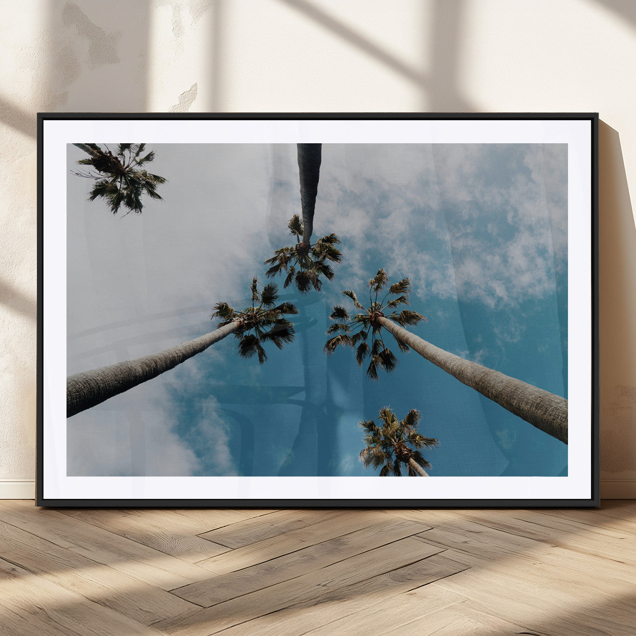 Looking up at tall palm trees against a bright blue sky with scattered clouds, creating a tropical and airy atmosphere for modern home decor.