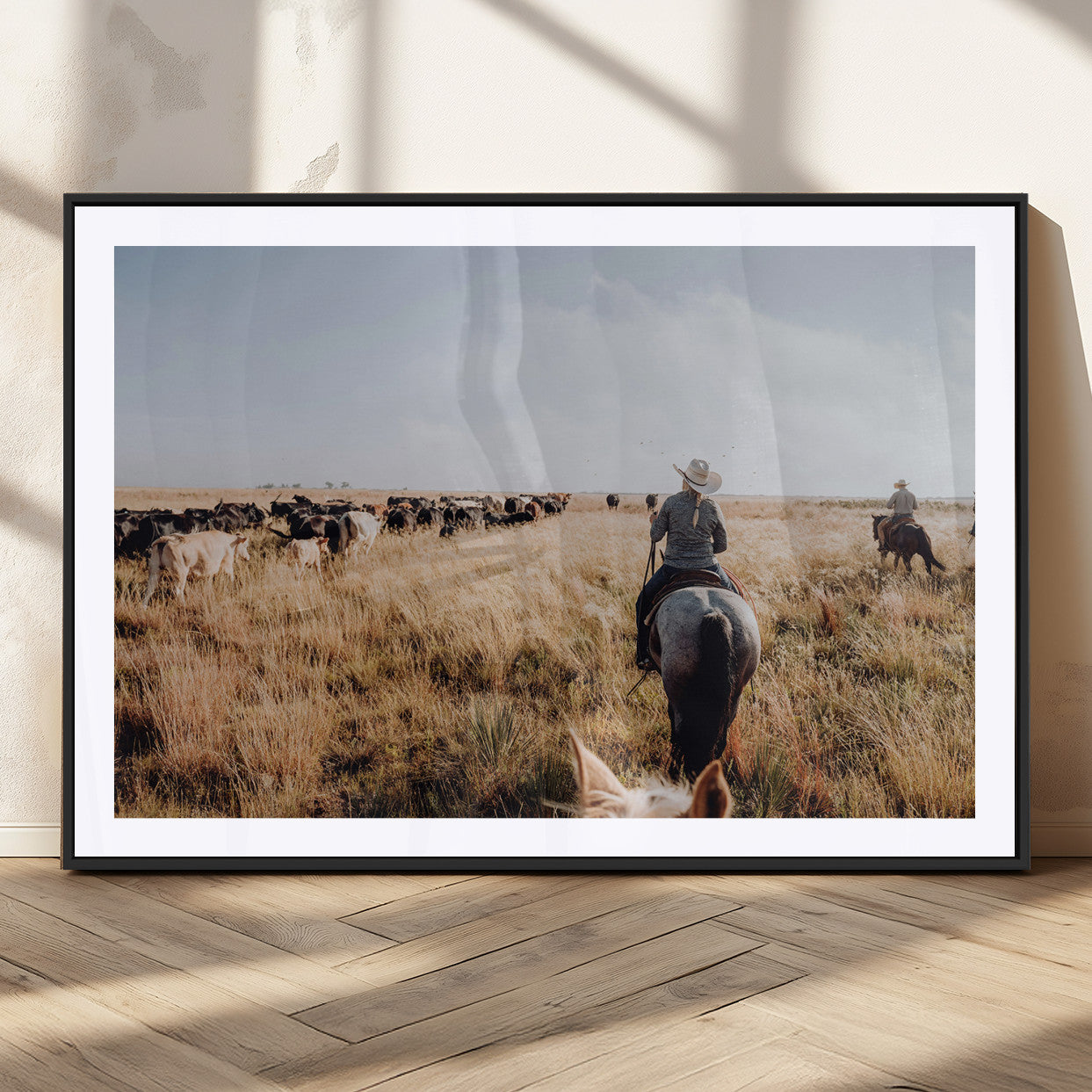 A cowboy and cowgirl on horseback herding cattle through golden grasslands, capturing a rustic and authentic Western ranch lifestyle.