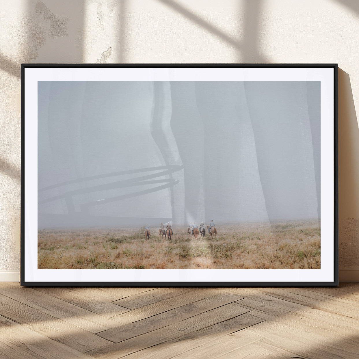 A group of horseback riders moving through a fog-shrouded field, evoking a calm Western scene with golden grasses and soft horizons.