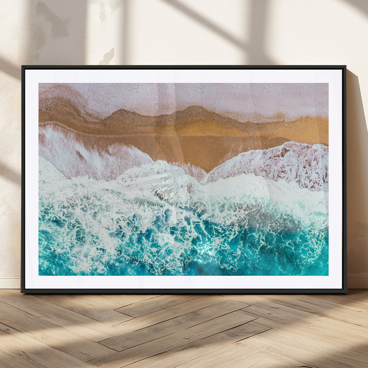 Aerial view of ocean waves crashing onto a sandy beach, with turquoise water and foamy white surf, creating a serene coastal aesthetic for home decor.
