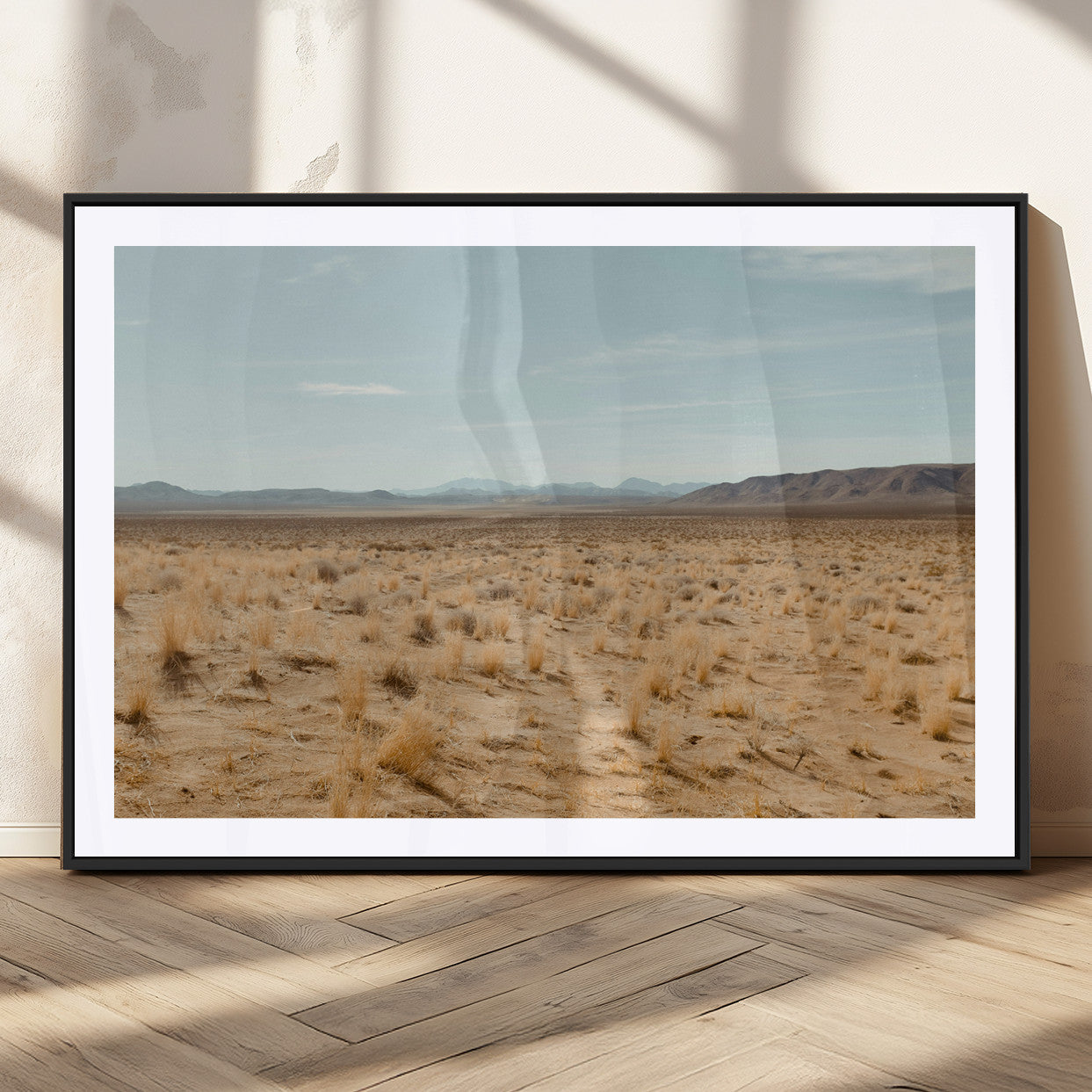 Expansive desert landscape with scattered dry grass and distant mountain range under a pale blue sky – Wall Art Canvas Print.