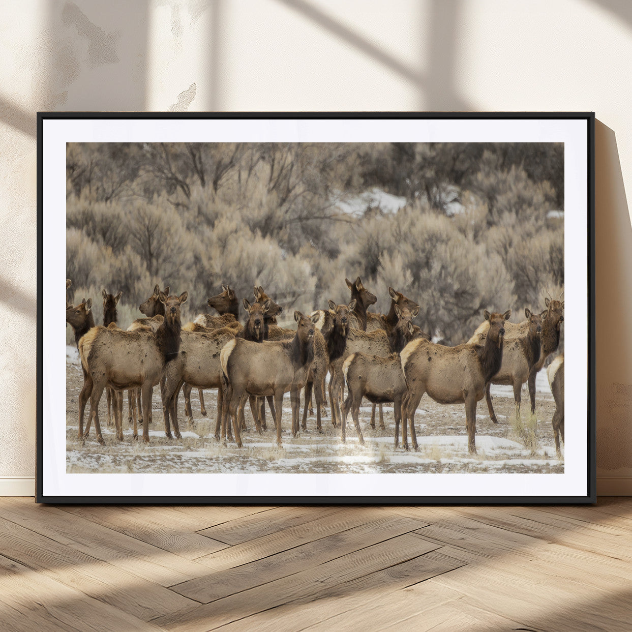 A stunning wall art canvas print featuring a large herd of elk standing together in a natural winter landscape with muted earthy tones and soft background foliage, perfect for rustic or nature-inspired home decor.