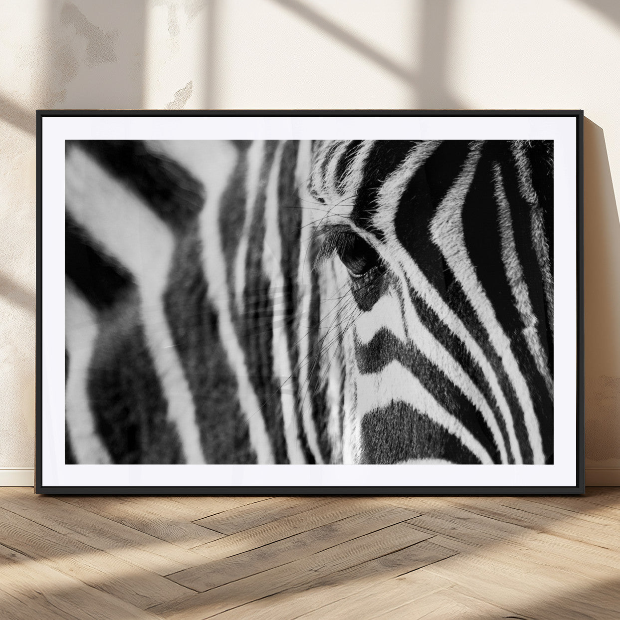 A close-up black and white photograph of a zebra's eye, showcasing the intricate patterns of its stripes in sharp detail.