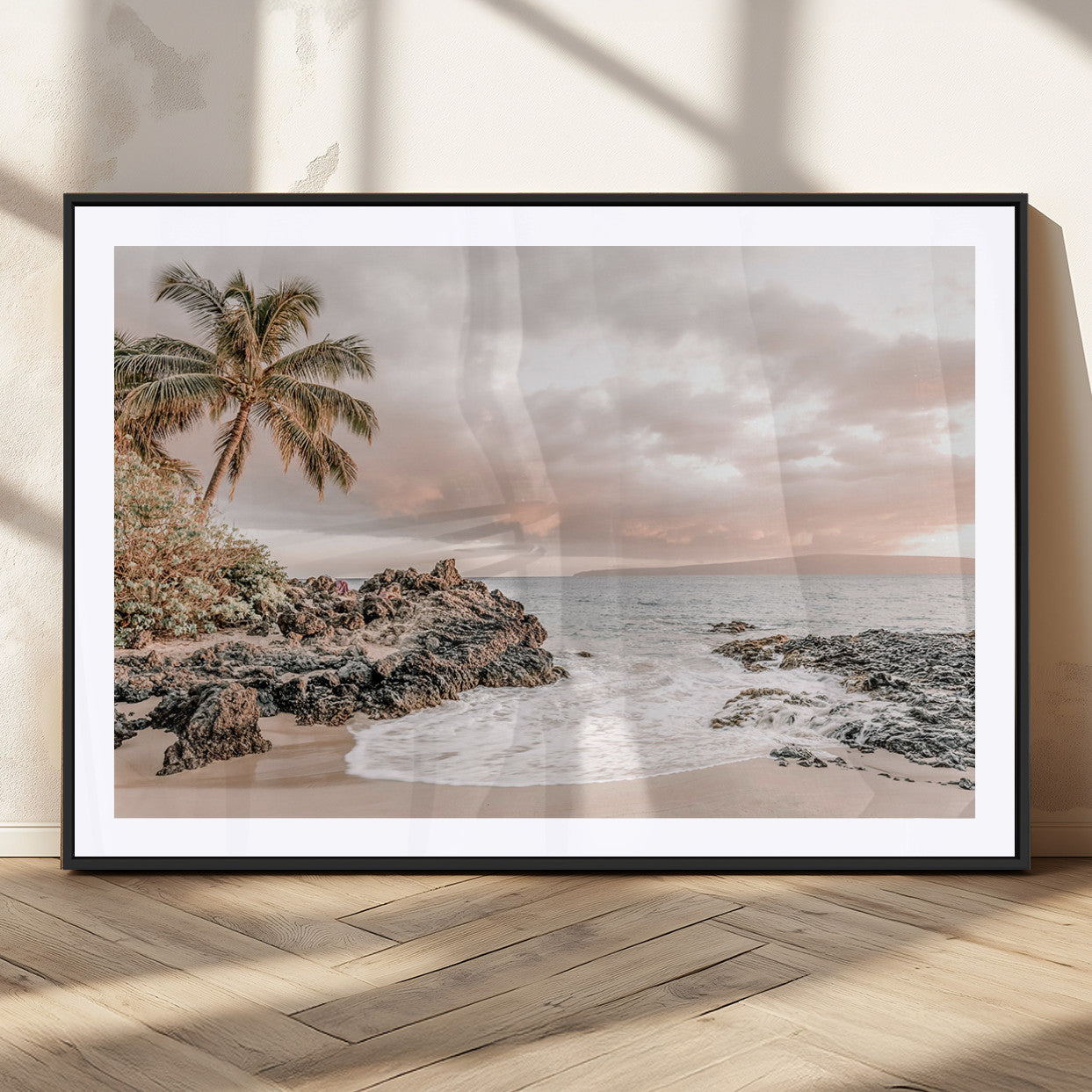 A peaceful beach scene with a palm tree and rocks, soft waves washing onto the shore under a soft pastel sky at sunset.