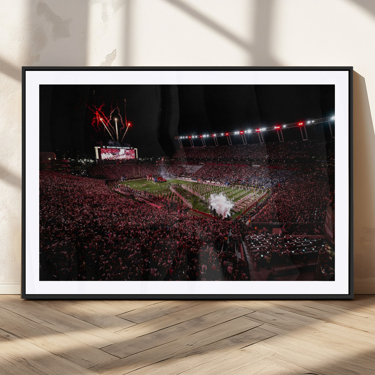 A dramatic shot of a packed stadium at night, with fireworks and smoke creating an exciting atmosphere for a live football game.