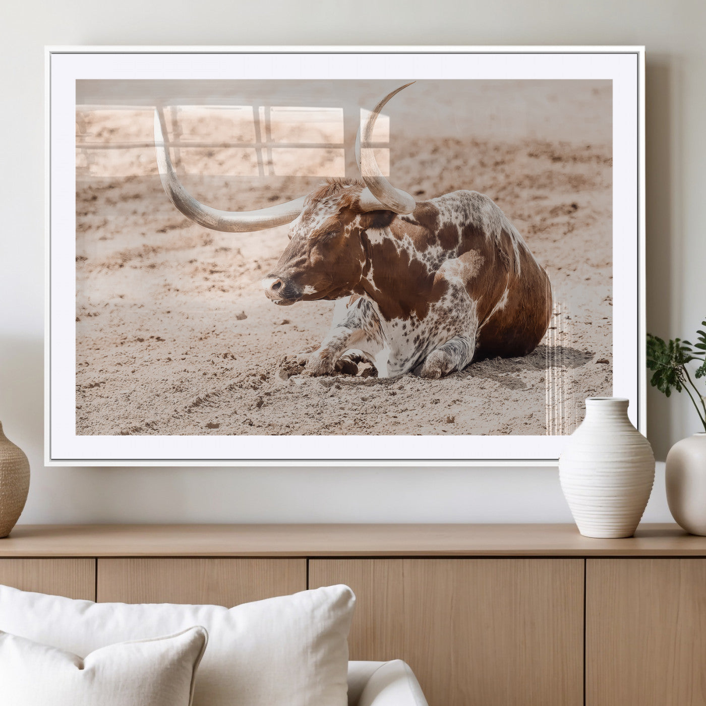 Texas Longhorn bull resting on dusty ground with warm tones, ideal for rustic western or farmhouse-themed wall decor.