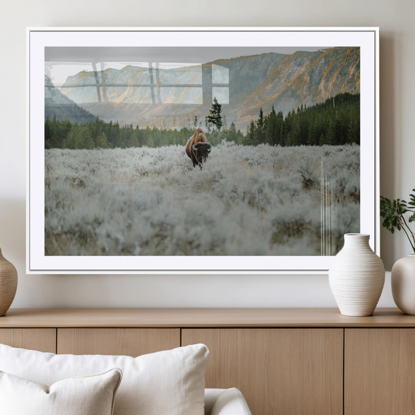 Lone bison standing in a frosted sagebrush field with a pine forest and rugged mountain range in the background under soft morning light – Wall Art Canvas Print.