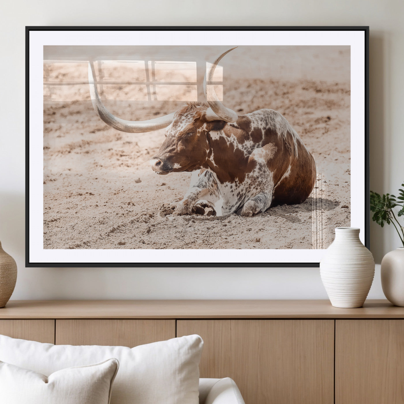Texas Longhorn bull resting on dusty ground with warm tones, ideal for rustic western or farmhouse-themed wall decor.