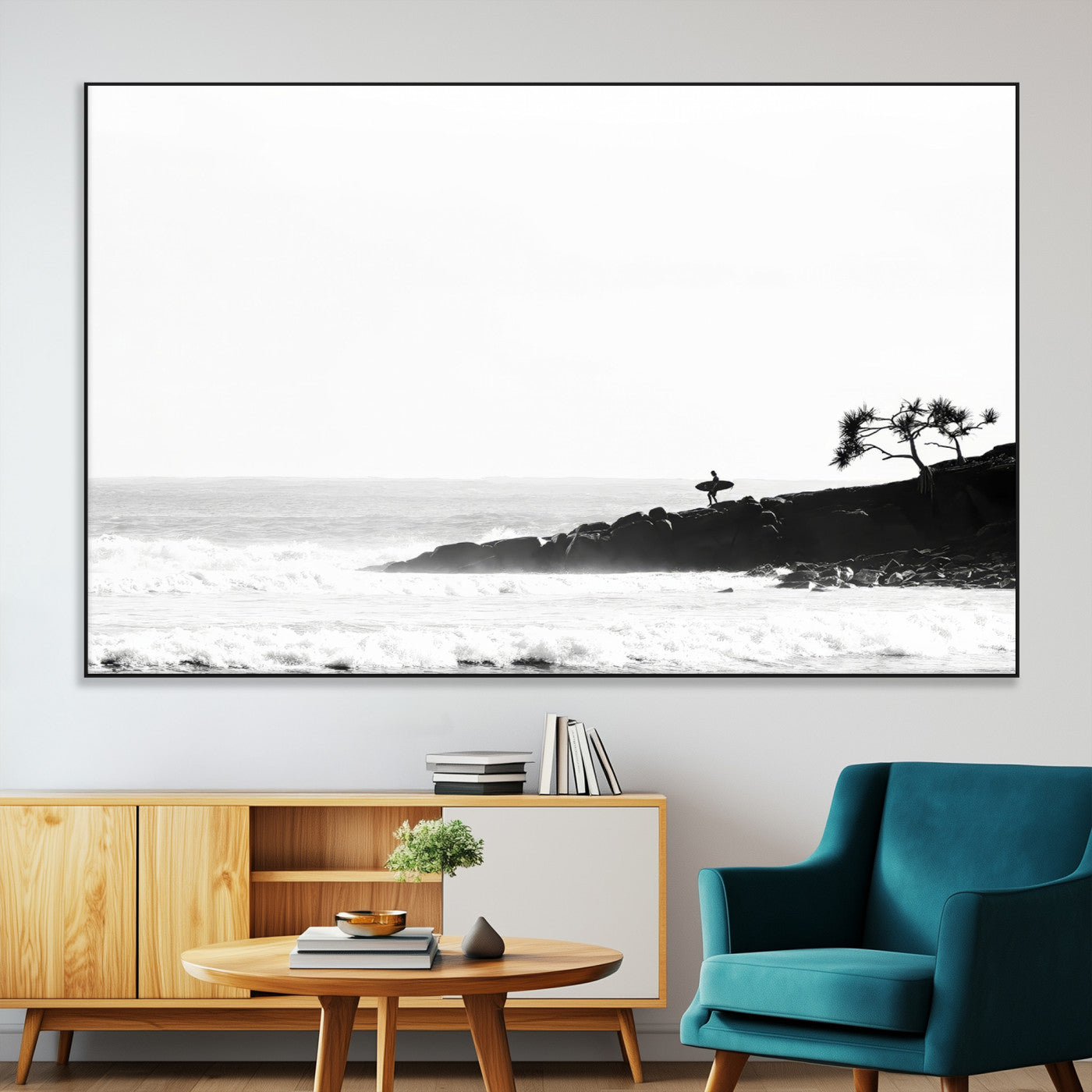 Black and white photo of a surfer standing on rocky cliffs, gazing at the waves, embodying the spirit of adventure and solitude.
