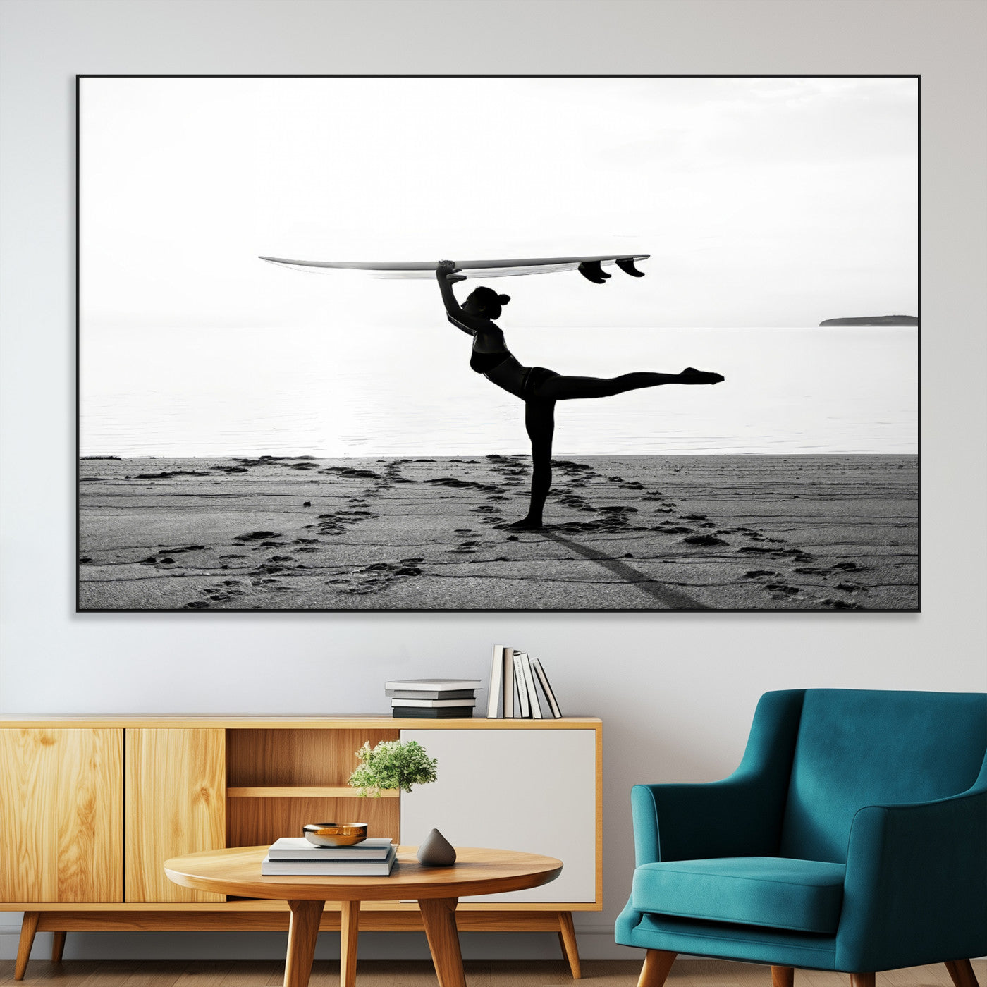 A woman balances a surfboard on her head while striking a yoga pose on the beach, silhouetted against a calm ocean horizon.