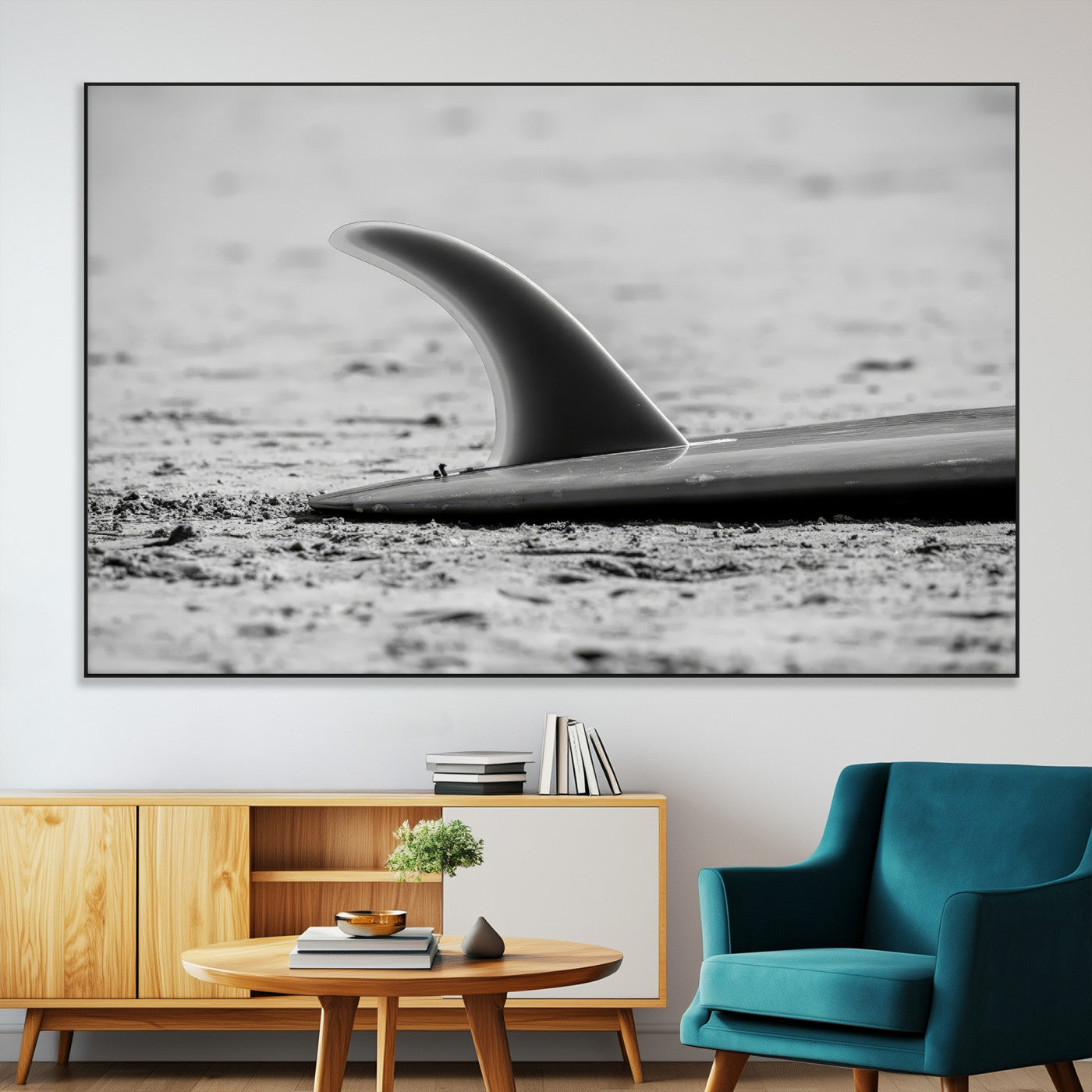 A black and white close-up of a surfboard fin resting on the sandy shore, highlighting minimalist beach aesthetics and classic surf culture.