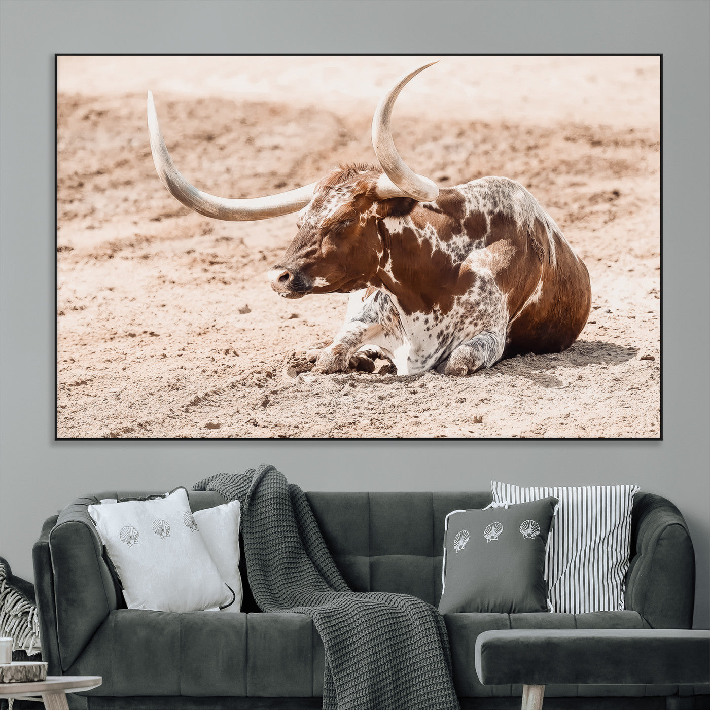 Texas Longhorn bull resting on dusty ground with warm tones, ideal for rustic western or farmhouse-themed wall decor.