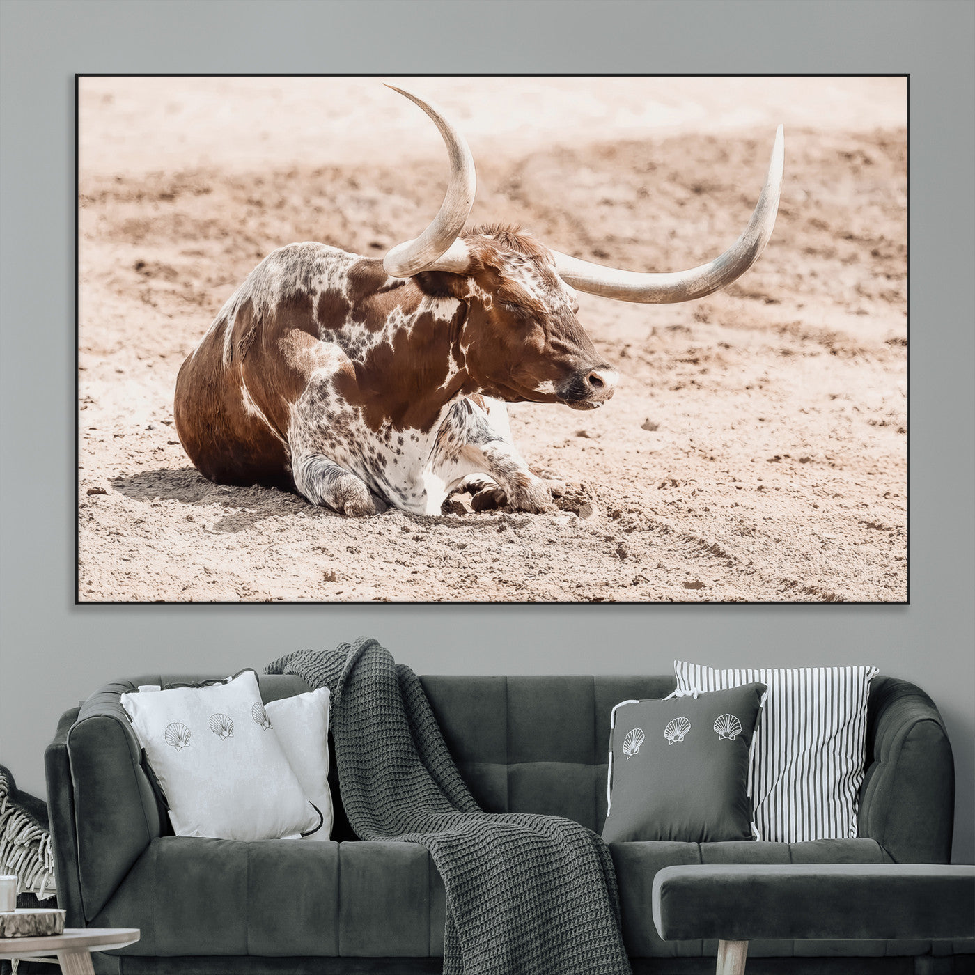 Texas Longhorn bull resting on dusty ground with warm tones, ideal for rustic western or farmhouse-themed wall decor.
