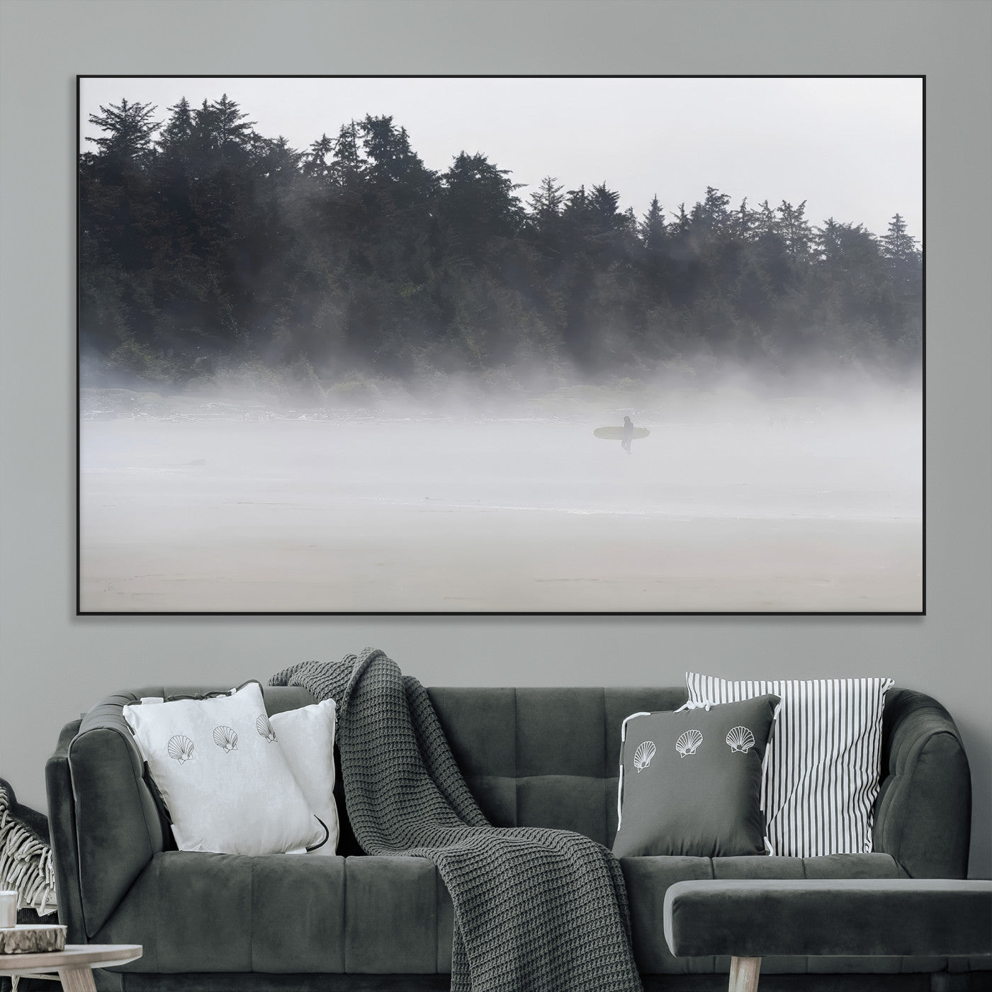 A lone surfer carrying a board through a misty shoreline, surrounded by dense trees and fog, creating a peaceful and mysterious coastal scene.