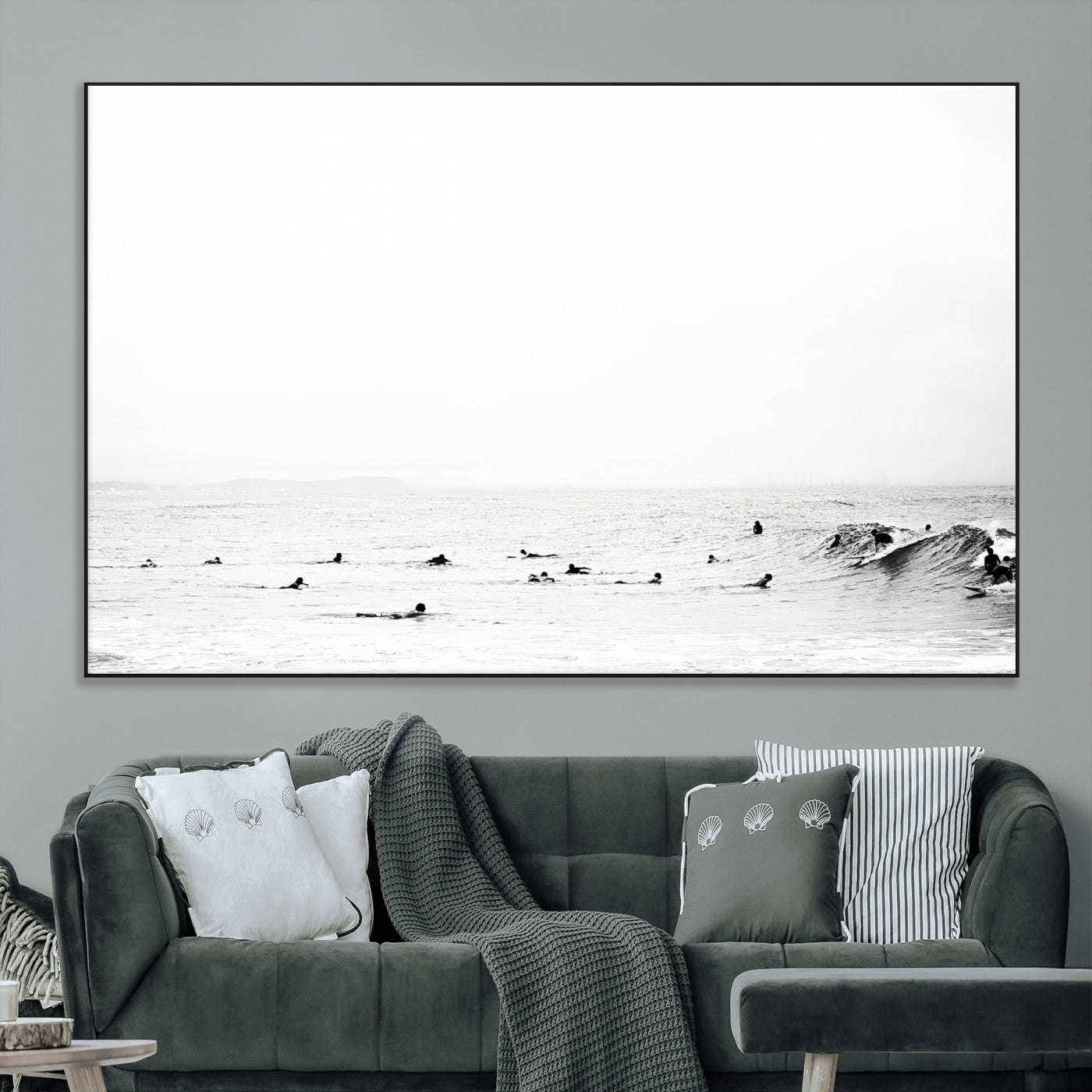 A group of surfers floating in the ocean, waiting for waves under a vast, moody sky, captured in black and white.