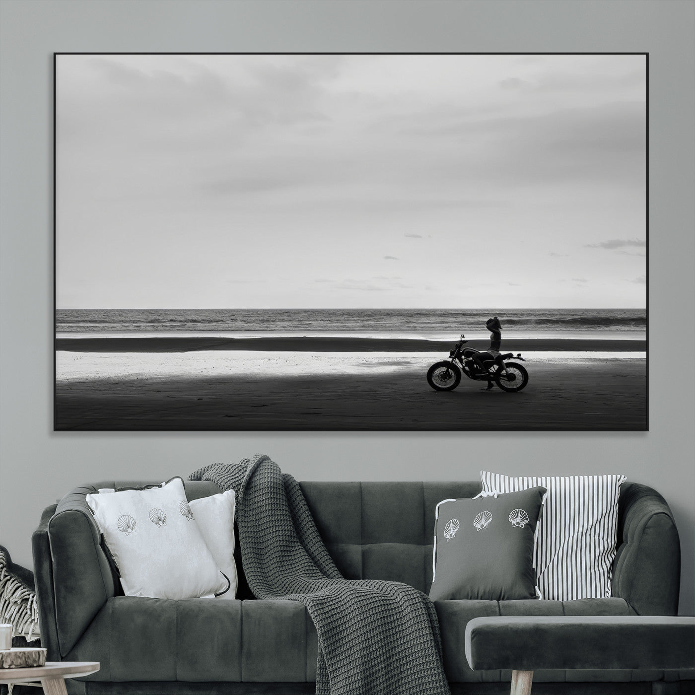 A motorcyclist on a vast beach, gazing at the ocean, capturing a moody and tranquil coastal adventure in black and white.