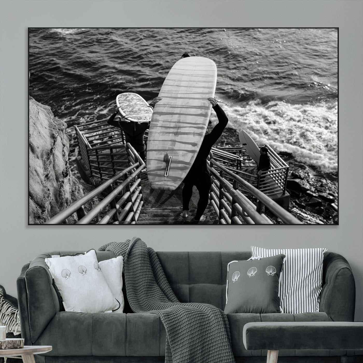 Black and white photo of surfers carrying boards down a rugged cliffside stairway, capturing a bold and adventurous coastal scene.