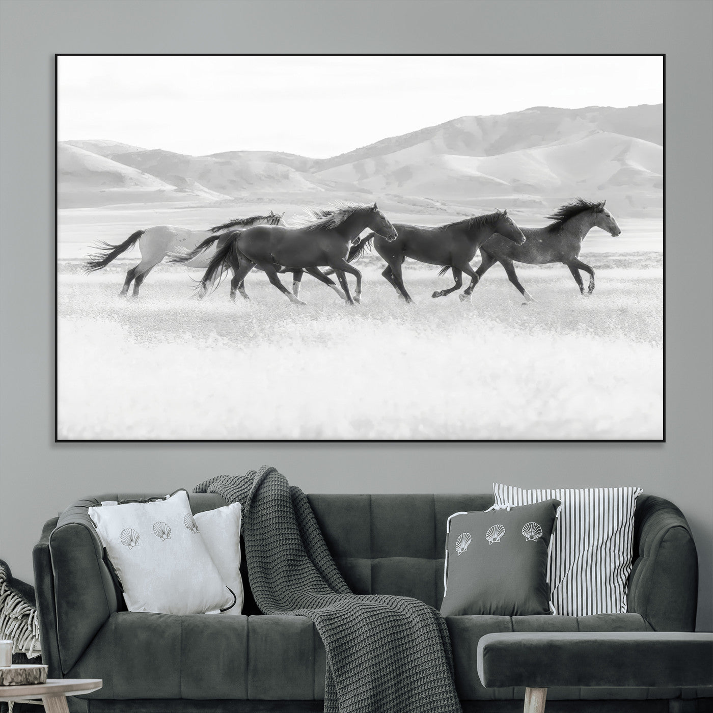 A black and white image of wild horses running freely across an open grassland, capturing the power and beauty of untamed nature in a rustic western setting.