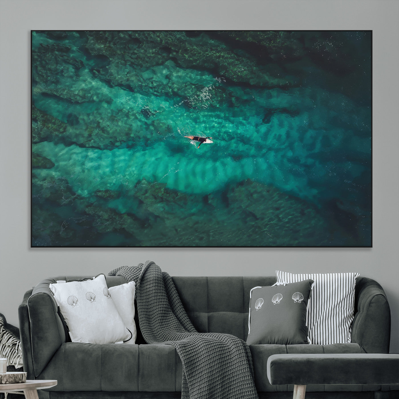 An aerial view of a solo surfer paddling through crystal-clear turquoise waters over a sunlit reef, capturing the beauty and serenity of open water surfing.