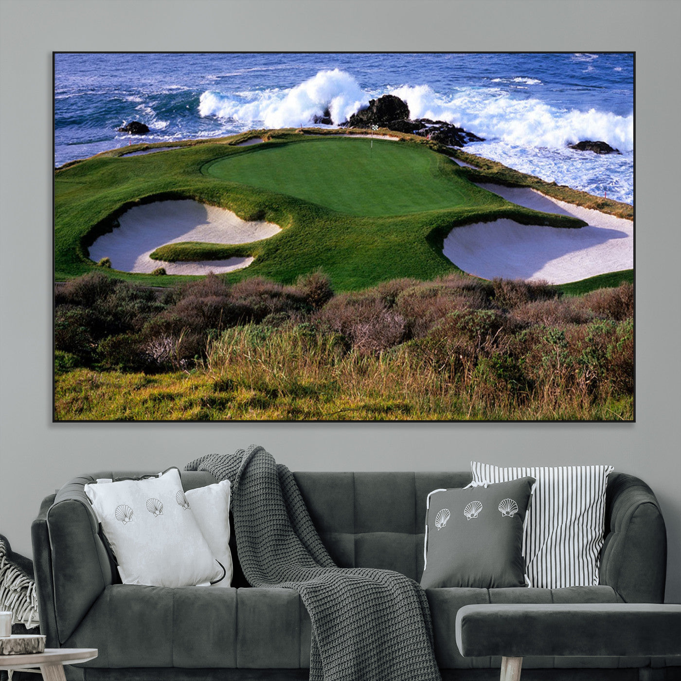 A scenic golf course located by the ocean, featuring a well-manicured green surrounded by sand traps and powerful ocean waves crashing on the shore.