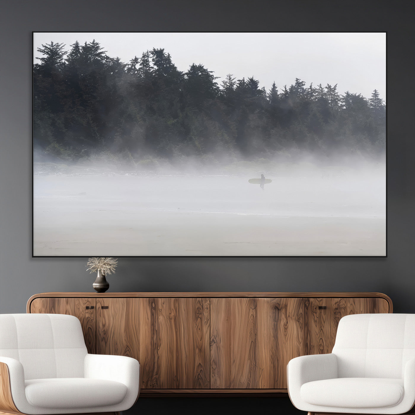 A lone surfer carrying a board through a misty shoreline, surrounded by dense trees and fog, creating a peaceful and mysterious coastal scene.