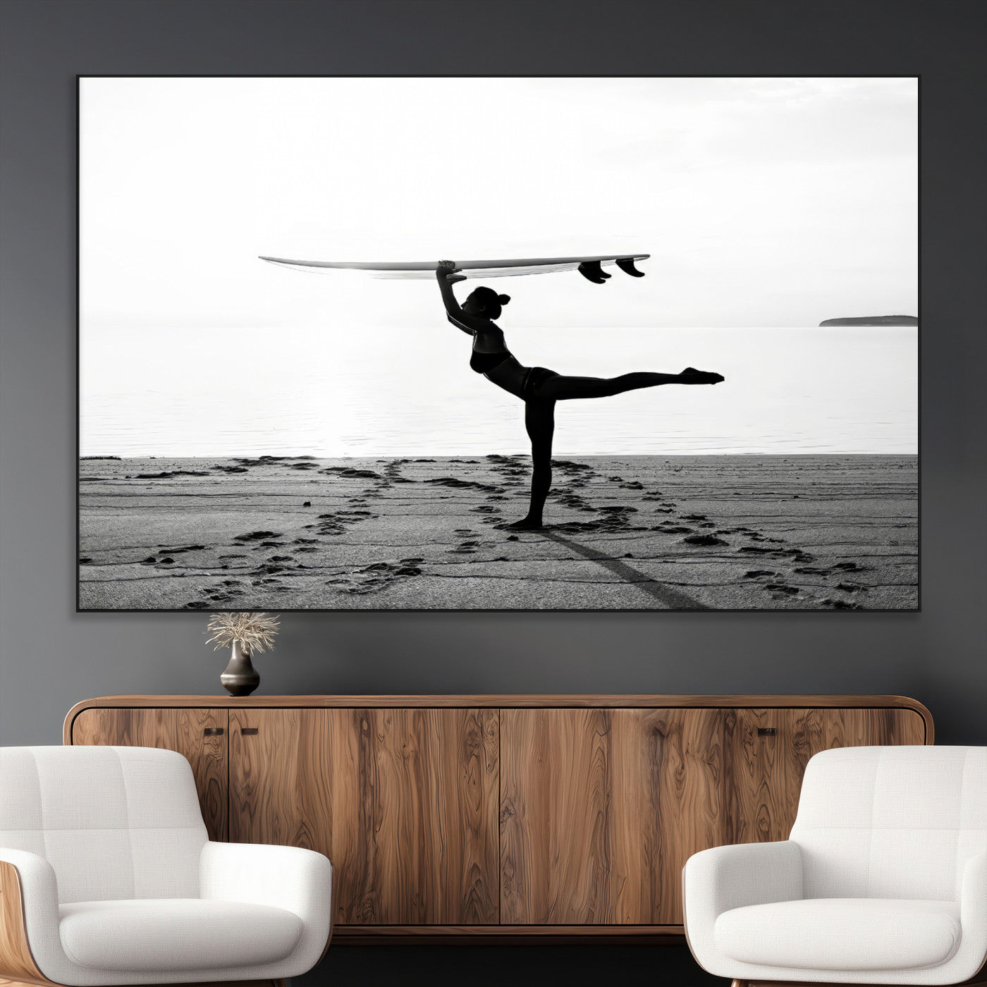 A woman balances a surfboard on her head while striking a yoga pose on the beach, silhouetted against a calm ocean horizon.