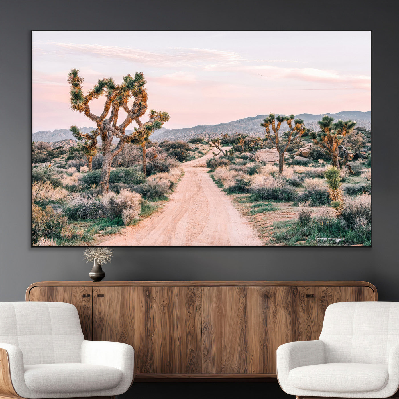 A dusty road winding through Joshua Tree National Park, framed by iconic twisted trees and warm desert tones under a soft pastel sky.