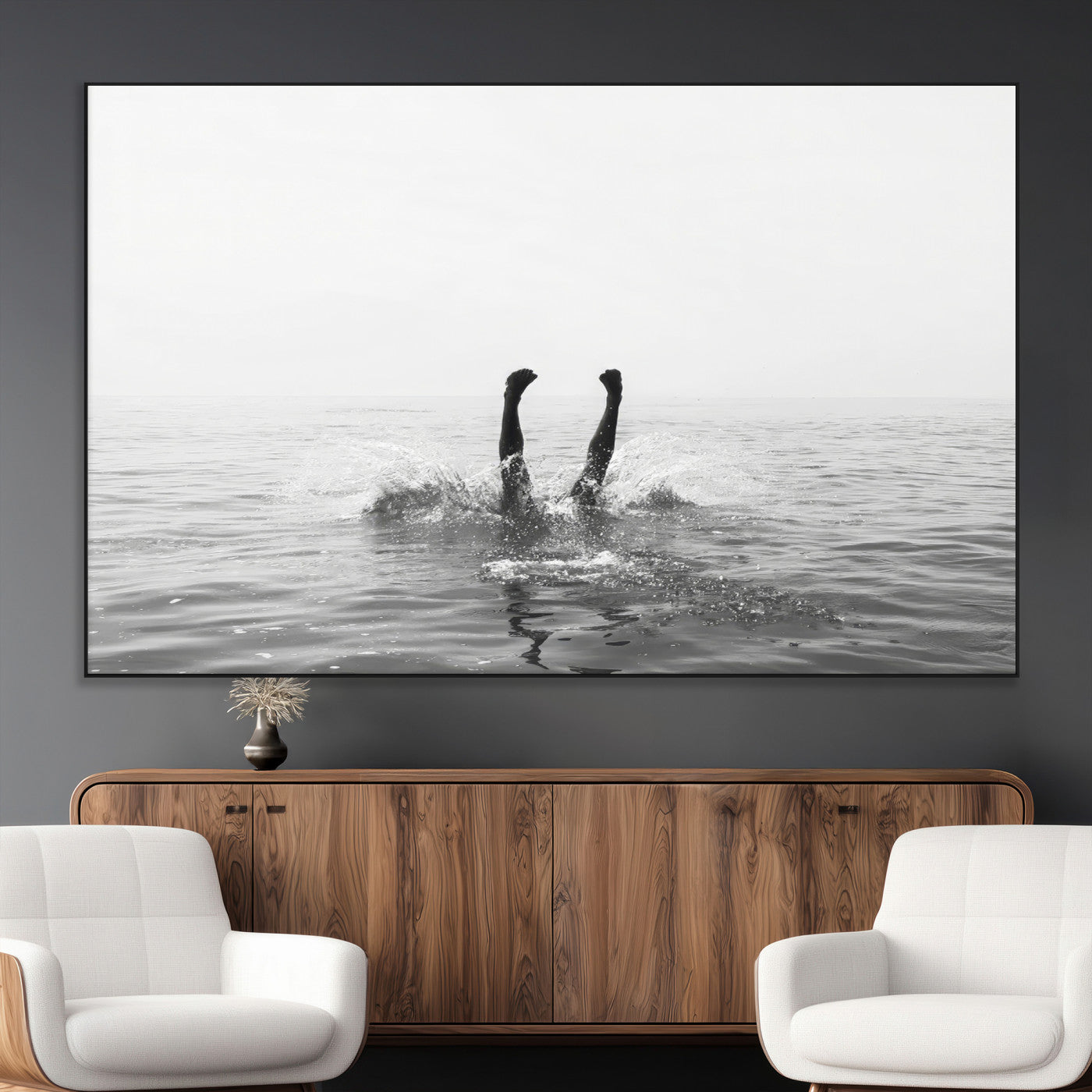 A black and white minimalist water scene capturing a playful splash as a swimmer dives upside down, creating a carefree and artistic aquatic aesthetic.