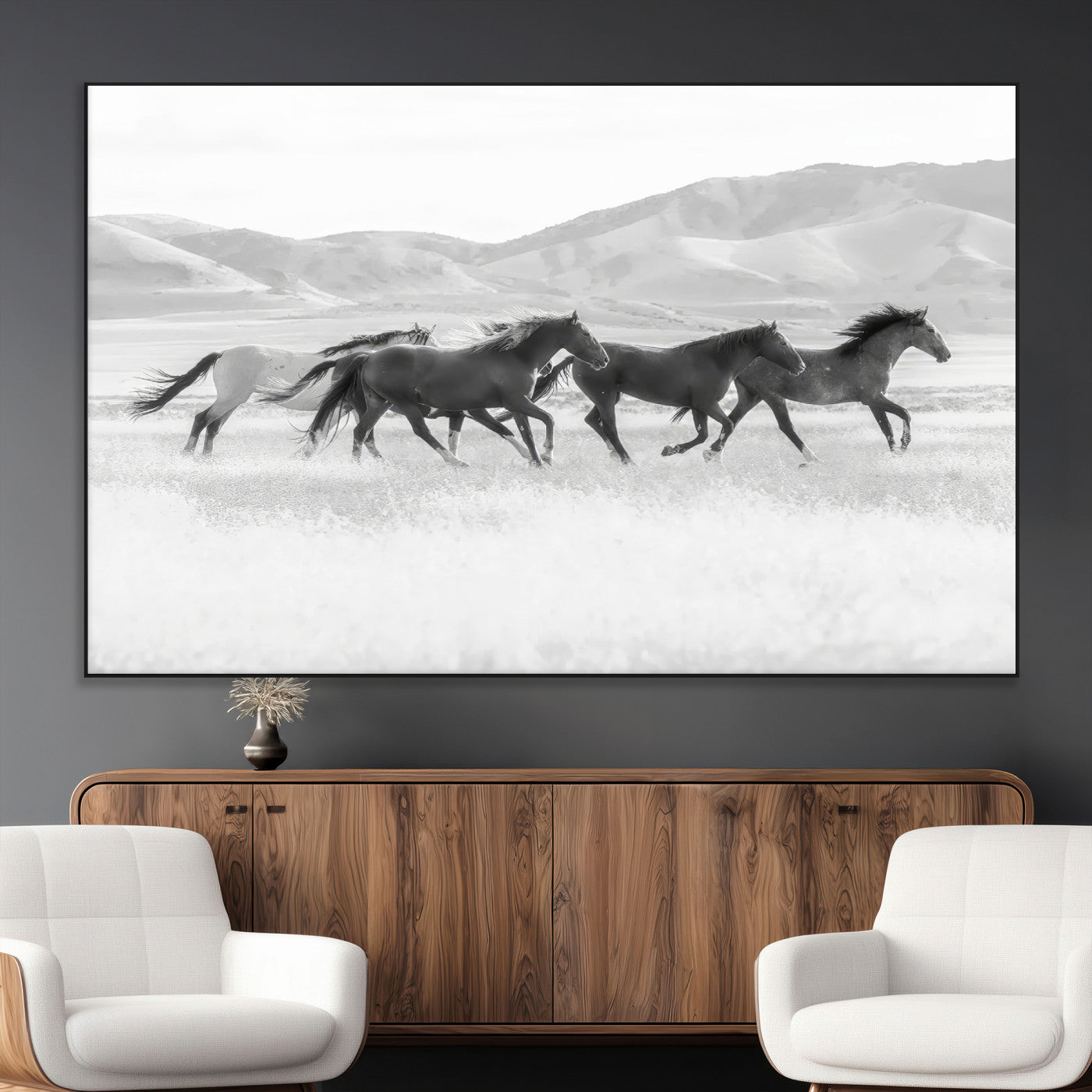A black and white image of wild horses running freely across an open grassland, capturing the power and beauty of untamed nature in a rustic western setting.