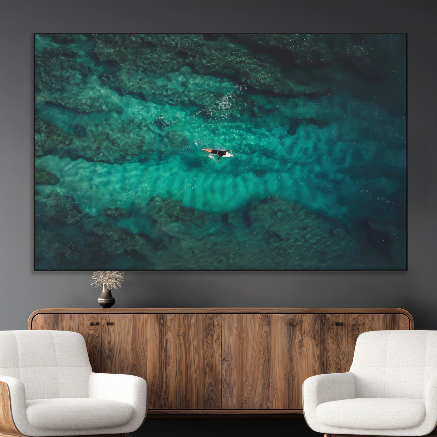An aerial view of a solo surfer paddling through crystal-clear turquoise waters over a sunlit reef, capturing the beauty and serenity of open water surfing.