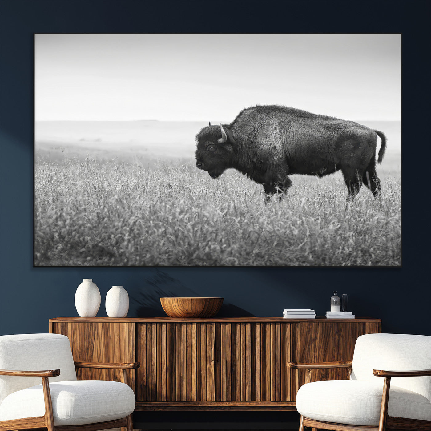 A black and white photograph of a majestic bison standing in a vast grassy prairie, evoking a sense of wilderness and strength.