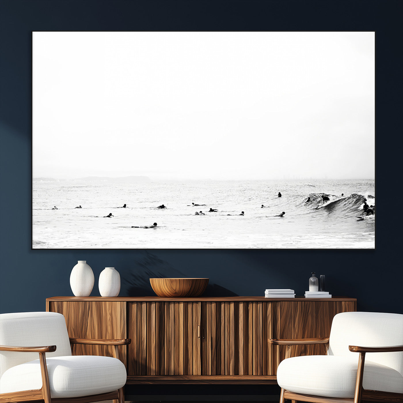 A group of surfers floating in the ocean, waiting for waves under a vast, moody sky, captured in black and white.