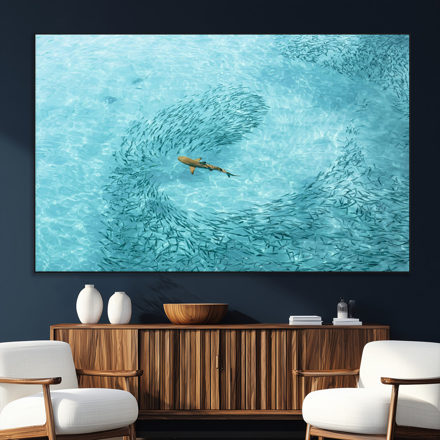 Aerial view of a shark swimming through a swirl of fish in clear turquoise waters, perfect for calm coastal or beach house decor.