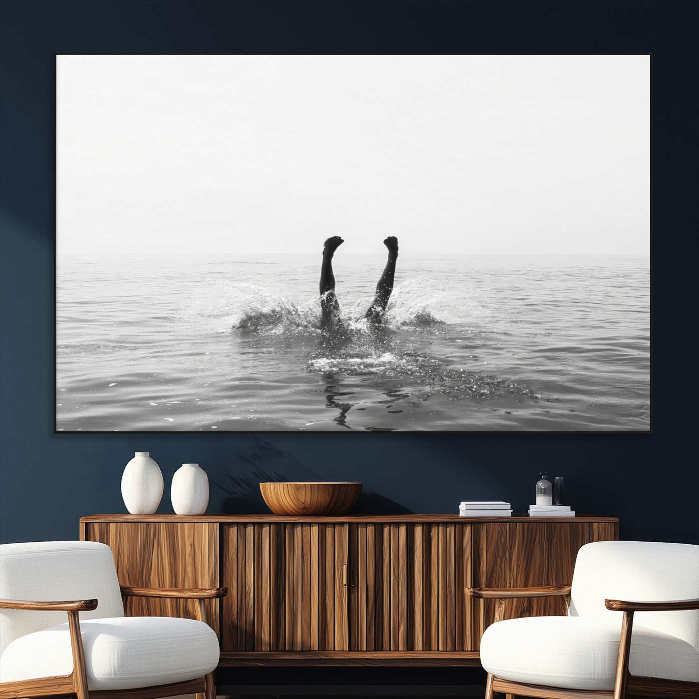 A black and white minimalist water scene capturing a playful splash as a swimmer dives upside down, creating a carefree and artistic aquatic aesthetic.