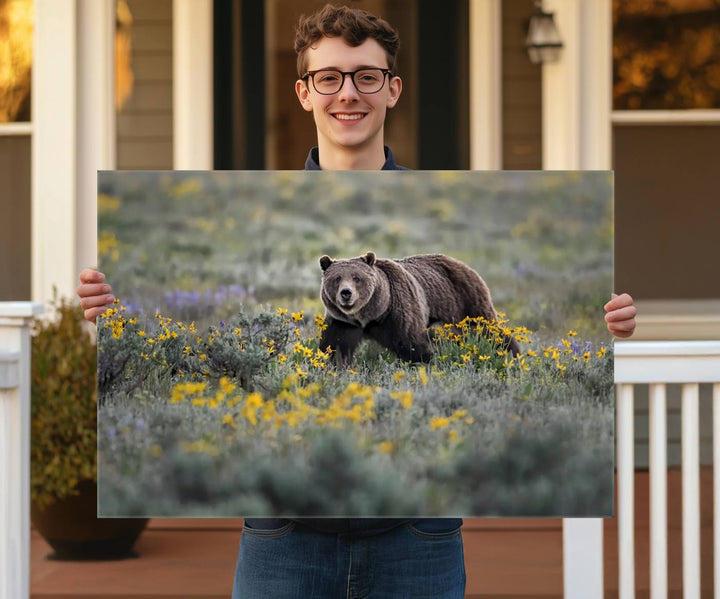 The "Grizzly 399 in Wild Flowers Wall Art Canvas Print" features a grizzly bear strolling through a field of yellow and purple flowers, beautifully showcased as a triptych. This handcrafted piece, proudly made in the USA, adds charm and sophistication to your space.