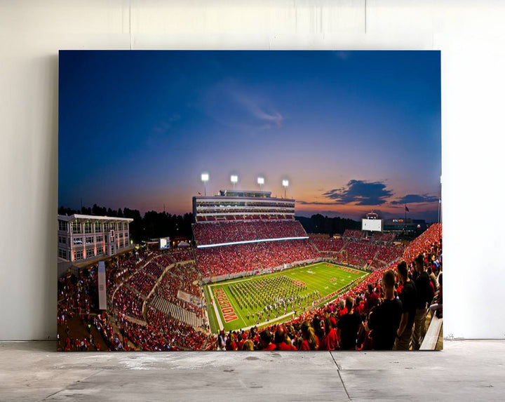 A vibrant and dynamic painting captures the essence of an electrifying night game at Carter-Finley Stadium, highlighting the illuminated atmosphere as the NC State Wolfpack competes under bright stadium lights.