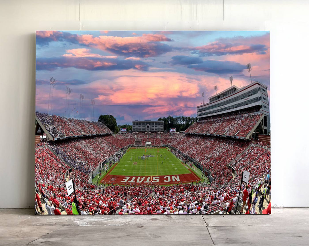 The wall art captures an NC State Wolfpack game under a vibrant sunset on triple canvas.