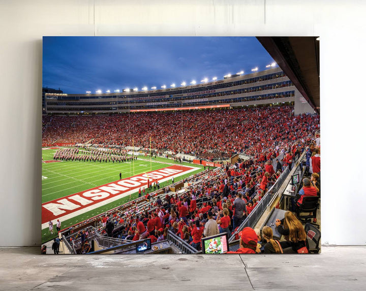 A vibrant wall art captures the essence of Madison Camp Randall Stadium, depicting a sea of fans in red and white during a Wisconsin Badgers football game under bright lights.