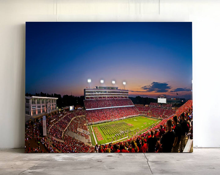 The Wolfpack Football Team Print captures a band and crowd at dusk in a premium canvas art style at Raleigh Carter-Finley Stadium.