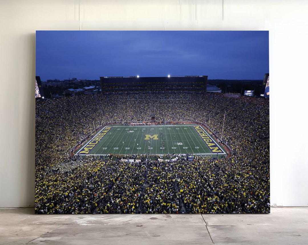 Wall art featuring an aerial shot of Michigan Stadium at dusk, showcasing the University of Michigan Wolverines M logo.