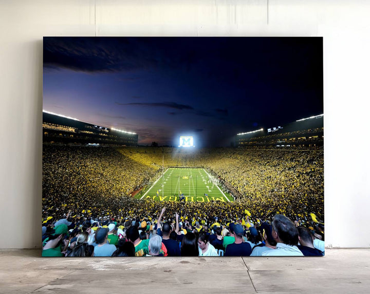 The wall art features a glowing M in this Michigan Wolverines Football Team Ann Arbor Stadium Canvas Print.